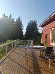 a wooden deck with a table and chairs on it at Vakker perle nær sjøen in Villanger +8 photos