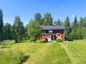 a red house in a field with a grass yard at Hus Fee in Fredriksberg