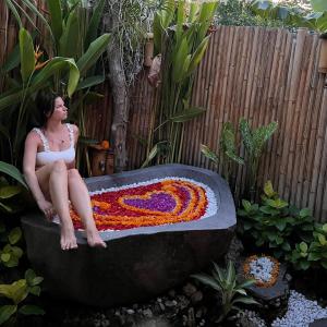 a woman sitting in a bathtub made out of flowers at Penida Bambu Green Suites in Nusa Penida