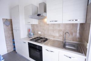 a kitchen with white cabinets and a sink and a stove at Costa Ovest - Goelba in Fetovaia