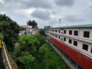 a row of white buildings with trees in front of them at Sandy Homestay in Dehradun