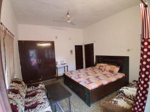 a bedroom with a bed and a chair in it at Sandy Homestay in Dehradun +2 photos