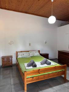 a bedroom with a wooden bed with green sheets at LYGIROS ANASTASIOS in Tarti