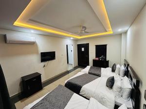a hotel room with two beds and a flat screen tv at Sapphire Stays Hotel And Restaurant in Peshawar