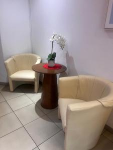 a room with two chairs and a table with flowers on it at Hotel Am Flughafen in Cologne