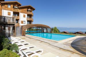 a swimming pool with lounge chairs next to a building at Résidence Odalys Les Chalets d'Evian in Évian-les-Bains