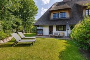 a chair and a table in front of a thatched house at Sommerhaus in Keitum