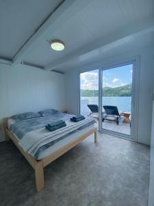 a bedroom with a bed and a view of the water at Viridian Three Boathouse Unique, PERUCAC in Perućac