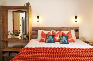 a bedroom with a bed with orange pillows and a mirror at The Pig Arc in Bude
