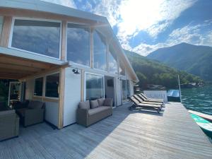 a house with chairs and a deck on the water at Viridian Three Boathouse Unique, PERUCAC in Perućac