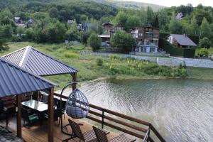 a deck with a table and chairs next to a lake at Villa Beti in Mavrovo