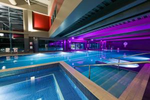 a large indoor swimming pool with purple lighting at Village Hotel London Watford in Elstree