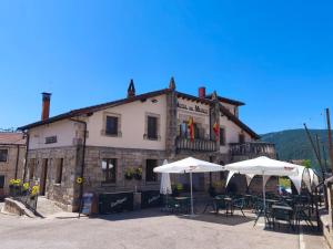 a building with tables and umbrellas in front of it at Hotel Rural del Médico in Regumiel de la Sierra