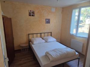 a bedroom with a bed with white sheets and a window at Maison proche bourg in Piégut-Pluviers