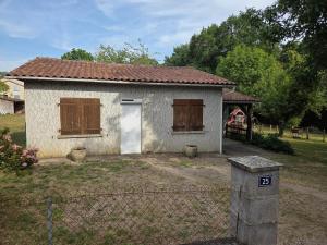 a small white house in a yard with a fence at Maison proche bourg in Piégut-Pluviers