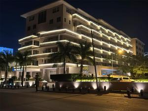 a large white building with palm trees in front of it at Afrin Prestige Hotel in Maputo
