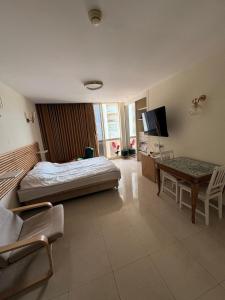 a bedroom with a bed and a table and a tv at חדר לים הרצליה in Herzliya B