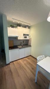 a kitchen with white cabinets and a sink and a table at LE VOLPI Marilleva 1400 in Marilleva