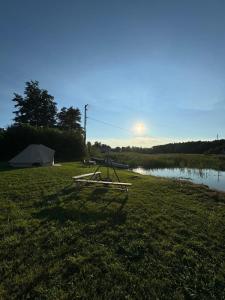a picnic table in the grass next to a lake at Jennys tent in Saltvik