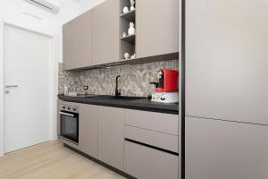 a kitchen with white cabinets and a red appliance at Perla Dell'Etna Holiday House in Zafferana Etnea