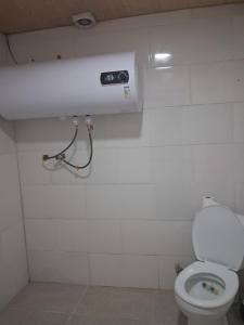 a bathroom with a white toilet and a light at Lama inn in Mestia