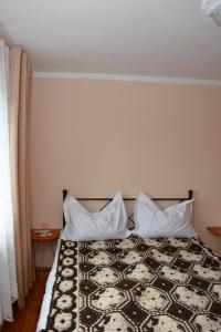 a bedroom with a bed with two pillows on it at Pensiunea Margareta in Sita Buzăului