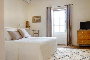 a white bedroom with a bed and a window at Maison Forte in Montcuq