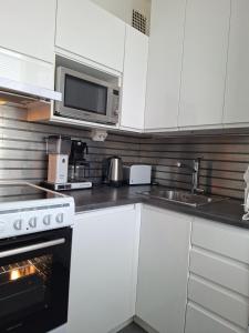 a kitchen with white cabinets and a sink and a microwave at City Apartment Hilla in Rovaniemi