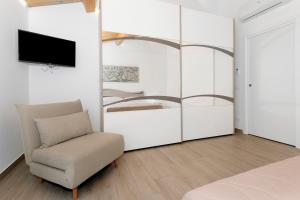a room with a bed and a chair and a television at Perla Dell'Etna Holiday House in Zafferana Etnea