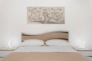 a bedroom with a bed with a tree picture on the wall at Perla Dell'Etna Holiday House in Zafferana Etnea