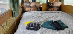 a bed with two pillows and towels on it at Pipowagen bij Sneek, voor maximaal 2 personen in Hommerts +21 photos