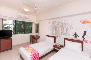 a bedroom with two beds and a tv at Ginger Thane in Thane