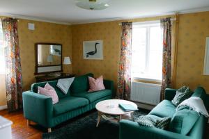 a living room with two green couches and a table at Wallby Säteri Gårdshotell & Konferens in Skirö