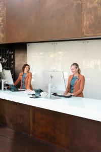 two women standing at a counter with a computer at Lido Palace - The Leading Hotels of the World in Riva del Garda