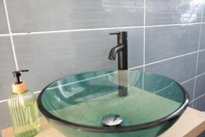 a glass sink with a faucet in a bathroom at Joli Cocon in Baie-Mahault