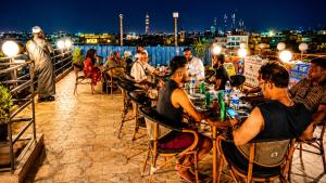 a group of people sitting at tables on a roof at night at Red Pyramids Hotel in Cairo +70 photos