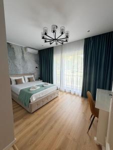 a bedroom with a bed with green curtains and a chandelier at Kaleh Boutique Villa in Orşova