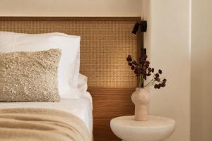a vase with flowers on a table next to a bed at Ilios Hotel, Adults Only in Laganas
