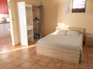 a bedroom with a bed and a tiled floor at Studio cosy aux Abymes, piscine et jardin, 25 m² in Les Abymes