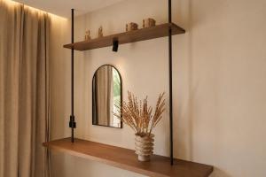 a room with a mirror and a vase on a shelf at Ilios Hotel, Adults Only in Laganas