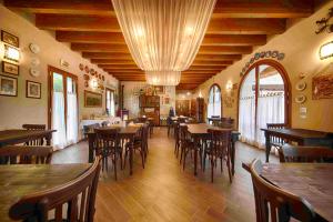 een restaurant met houten tafels, stoelen en ramen bij Agriturismo La Boschina in Crema