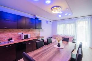 a kitchen and dining room with a wooden table and chairs at AH-Corso Wellness Apartment in Siófok