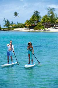 
a man and a woman paddle boards in the water at Constance Prince Maurice in Belle Mare
