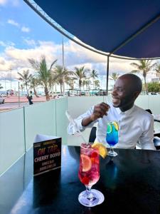 a man sitting at a table with a drink at Gooderson Tropicana Hotel in Durban