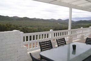 a table and chairs on a balcony with mountains in the background at Chalet Eland in Ladismith +6 photos