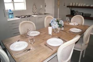 a wooden table with chairs and plates and wine glasses at Chalet Eland in Ladismith