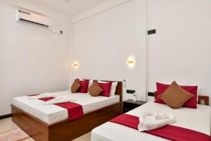 two beds in a room with red and white sheets at Bay Marina in Arugam Bay