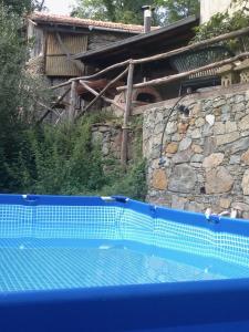 a blue swimming pool in front of a stone wall at B&B PETITE PROVENCE Genova in Ceranesi