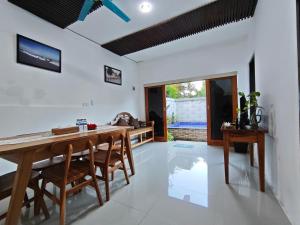 a dining room with white walls and a wooden table and chairs at Puri Sadewa Balangan in Jimbaran