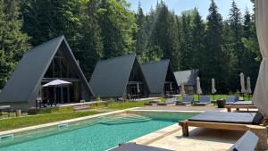 a resort with a pool and some chairs and trees at Ultra house будиночки в лісі біля гірської річки in Verkhovyna